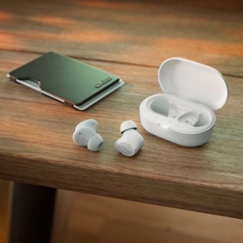 Philips T1209 TWS-oordopjes en oplaadcase op tafel Witte Philips T1209 TWS-oordopjes op tafel, met oplaadcase en kaartportemonnee ernaast.